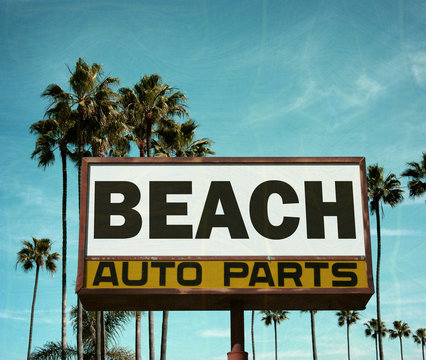 aged and worn vintage photo of auto parts sign with palm trees