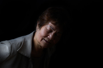 Senior woman showing back pain on black background