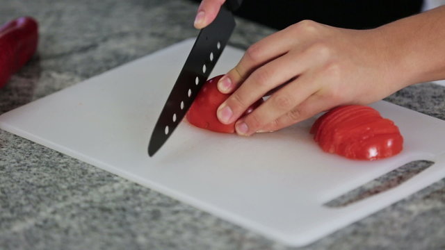 Close up video of hands cutting vegetables on a stone table, indoors in a kitchen. 