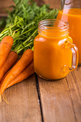 Carrot juice in mason jar on wooden background