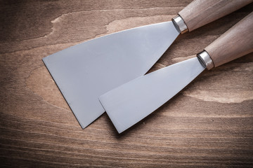 two paint scrapers on wooden board