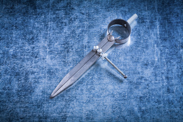 Pair of construction compasses on scratched metallic background