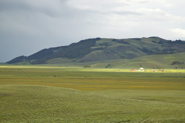 Fototapeta premium Storm clouds and sunlight on farm in distance of Centennial Valley, MT