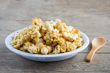Popcorn in a white cup on a wooden background.