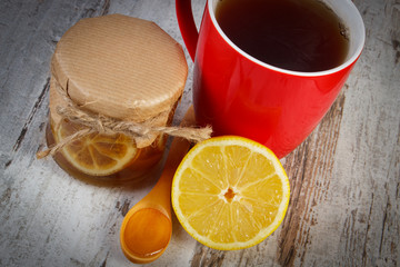 Lemon with honey and cup of tea on wooden table, healthy nutrition