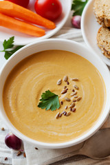 Vegetarian vegetable cream soup with eggplant and carrots in white bowl on wooden table, selective focus