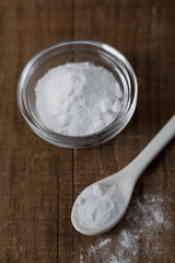 Baking soda, Sodium bicarbonate in glass bowl and spoon on wooden table