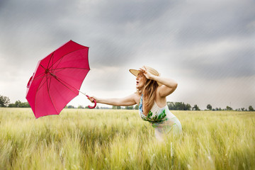 pretty woman with umbrella in a field of wheat ears
