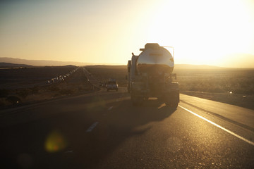 Fuel truck drives into setting sun on Interstate 15 in California.