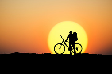Fototapeta na wymiar Silhouette of a biker on the mountain top. Sport and active life concept..