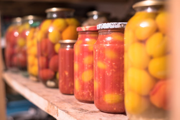 Fototapeta na wymiar Pickled Canned Tomatoes in a Raw on the Wooden Shelf