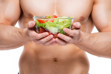 Young man with perfect body holds salad.