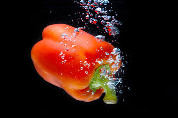 Fresh Red Bell Pepper Splash in Water on Black Background.