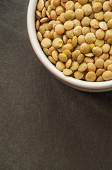 raw brown lentils close up on dark background