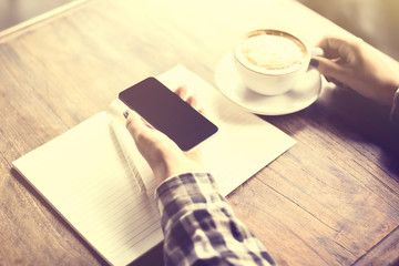 Girl hands with cappuccino, cell phone and blank diary, vintage