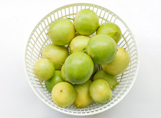 fresh limes in plastic basket on white