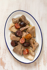 meat with sausages on dish on white wooden background