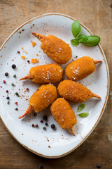 Breaded crab claws with basil and spices on a plate, top view