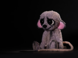 Sad little stuffed animal mouse toy alone in black background