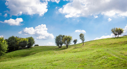 Fototapeta na wymiar green hills and midday blue sky with clouds
