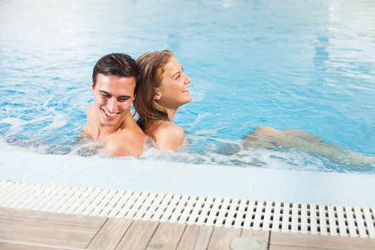 Happy couple in swimming pool enjoying hydromassage