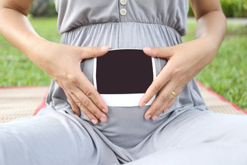 Pregnant women show ultrasound film picture on her belly.