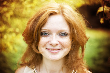 Fototapeta premium Portrait of redhead girl with blue eyes on nature