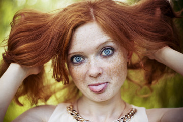 Portrait of redhead girl with blue eyes on nature