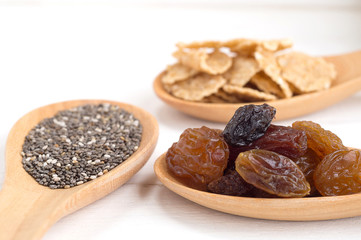 Set of raisins, whole wheat grain flakes and chia seeds in woode