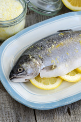 Raw trout stuffed with lemon slices and seasoned with aroma sea salt with lemon peel