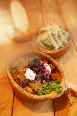 Goulash in ceramic pot/Delicious goulash served with fresh bread and portion of gnocchi