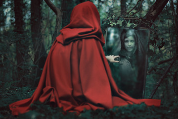 Mysterious hooded woman in front of a magical mirror