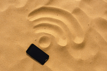 mobile phone lying on the beach, in the sand, which drafted the WiFi sign
