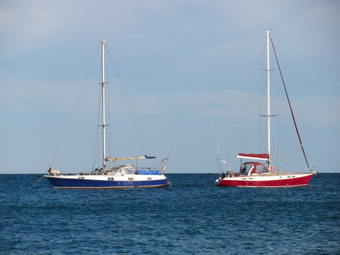 Fototapeta Two anchored yachts with deflated sails on the sea 