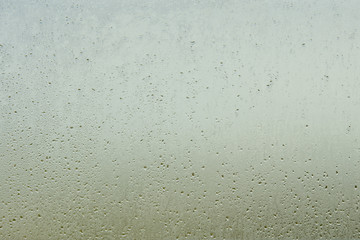 Abstract background water droplet on a restroom window with shading sunlight (Blurred wallpaper)