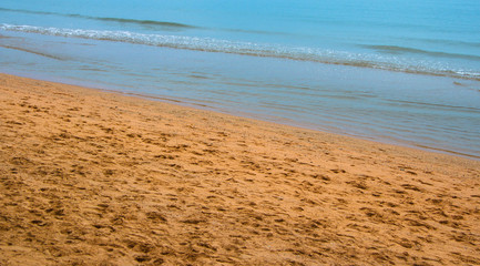 shore beach with traces of legs and a calm sea