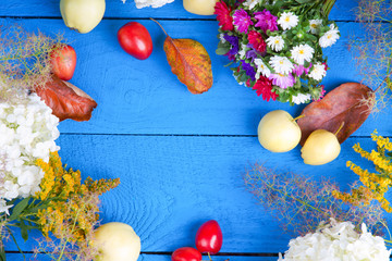 Apples, flowers, leaf litters and plums on a table