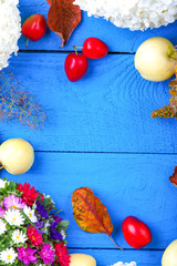 Apples, flowers, leaf litters and plums on a blue table 