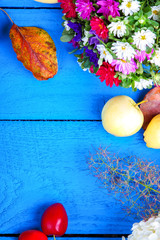 Apples, flowers, leaf litters and plums on a wooden table 