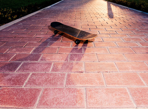 Vintsge skateboard on paved surface backlit. Toned image
