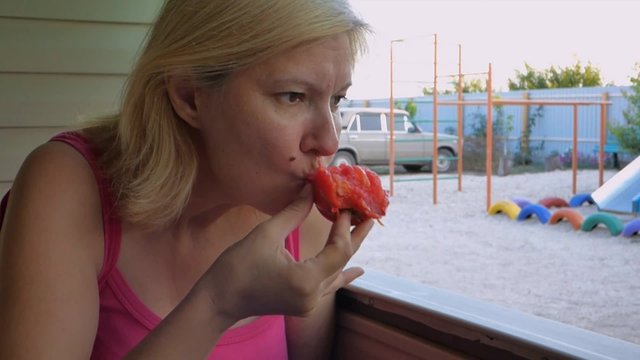 A woman eats red, juicy tomatoes