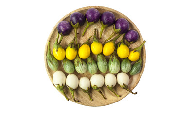 fresh white, green, yellow, purple eggplants in wooded plate on white background