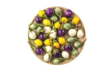 fresh white, green, yellow, purple eggplants in wooded plate on white background