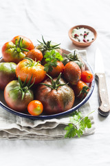 fresh tomatoes on a white enamel plate on a light surface