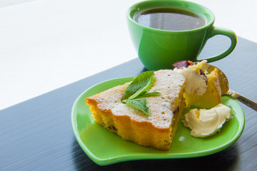 Slice of plum cake on plate, with cup of tea