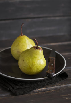 fresh yellow pears on a brown plate on a dark wooden surface