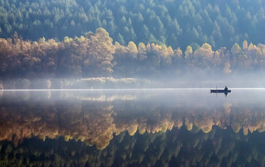 Un pêcheur à la ligne sur un lac brumeux.