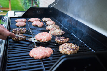 Man flipping hamburgers on grill