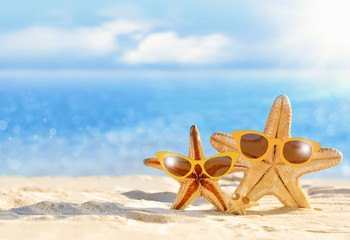 Fototapeta na wymiar Starfish in yellow sunglasses on the summer beach