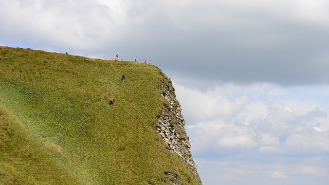 People with backpacks climbing a mountain in summer